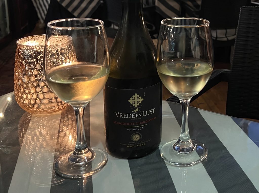 Two glasses of white wine and a candle on a striped table in a Clarens restaurant