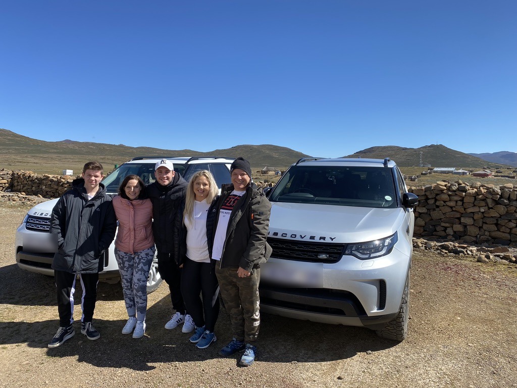 Five people standing in front of two luxury 4x4s in the Lesotho highlands